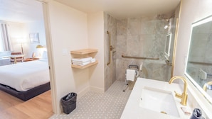 A hotel room with a bed, a bathroom with a shower, and a sink. -  The Atlas Hotel & Lofts (Goodlettsville)