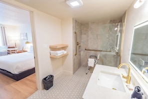 Ein Hotelzimmer mit Bett, Badezimmer mit Dusche und Waschbecken.