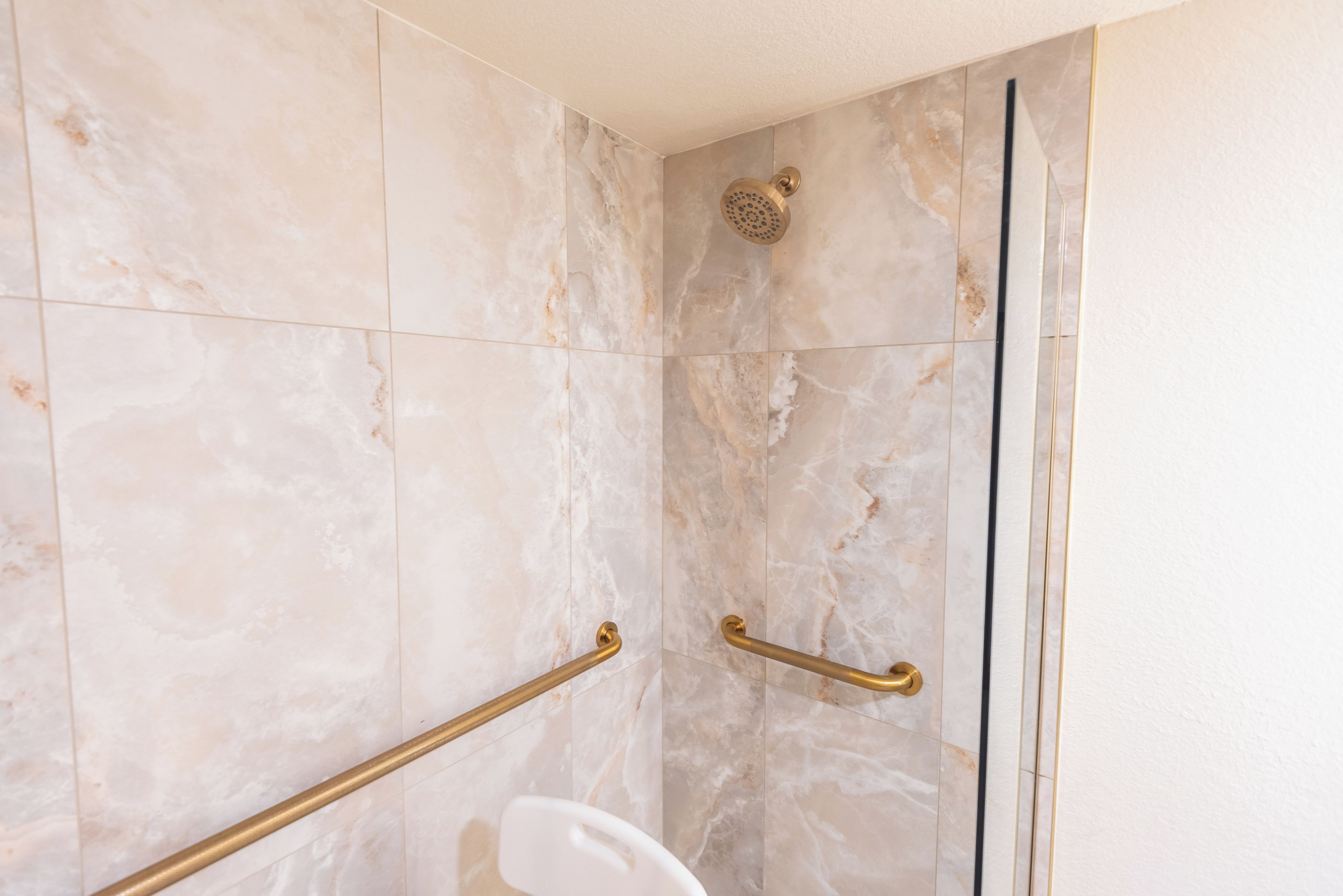 A shower with a handheld showerhead and a glass door.
