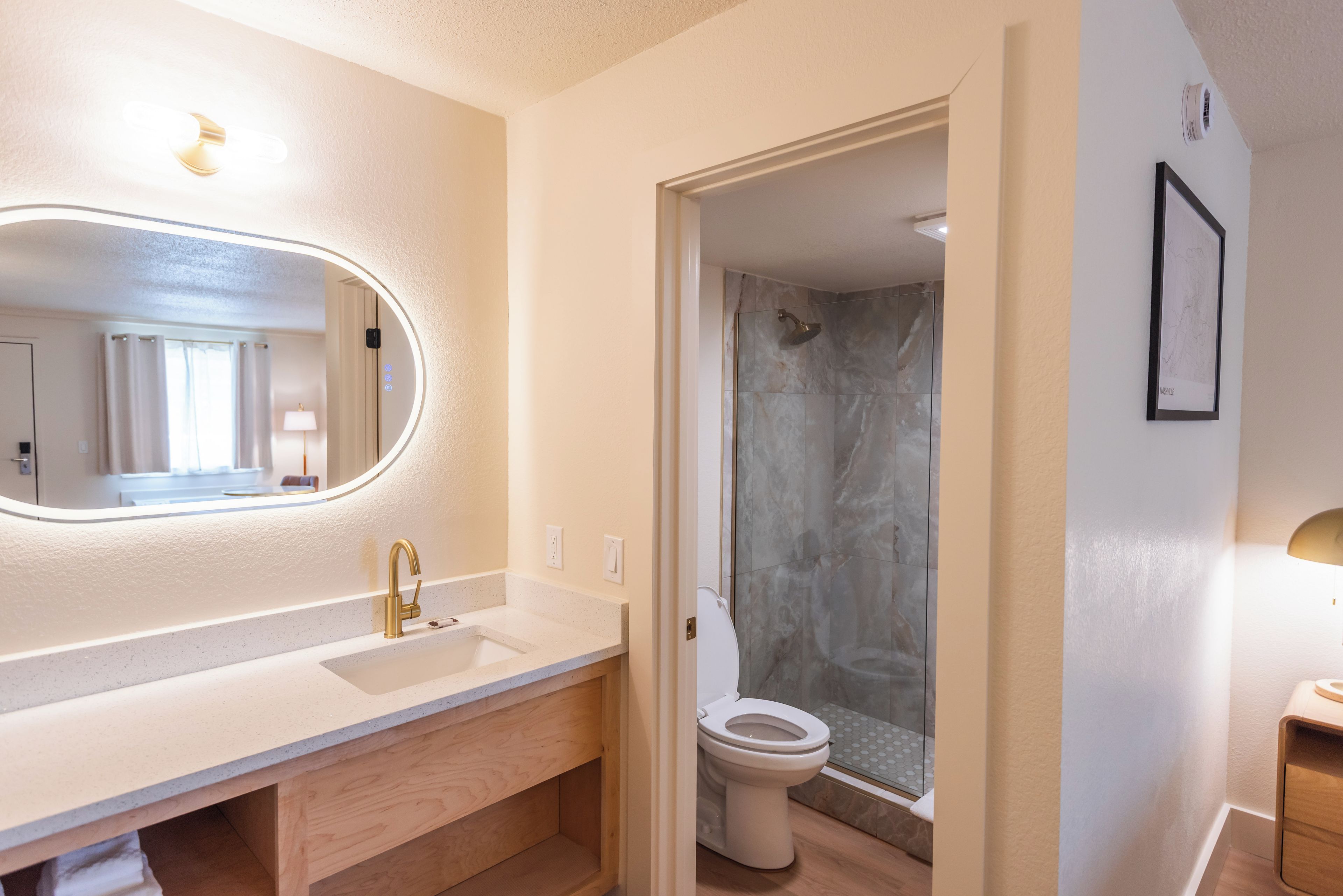 A bathroom with a white sink, a mirror, a shower, and a toilet.