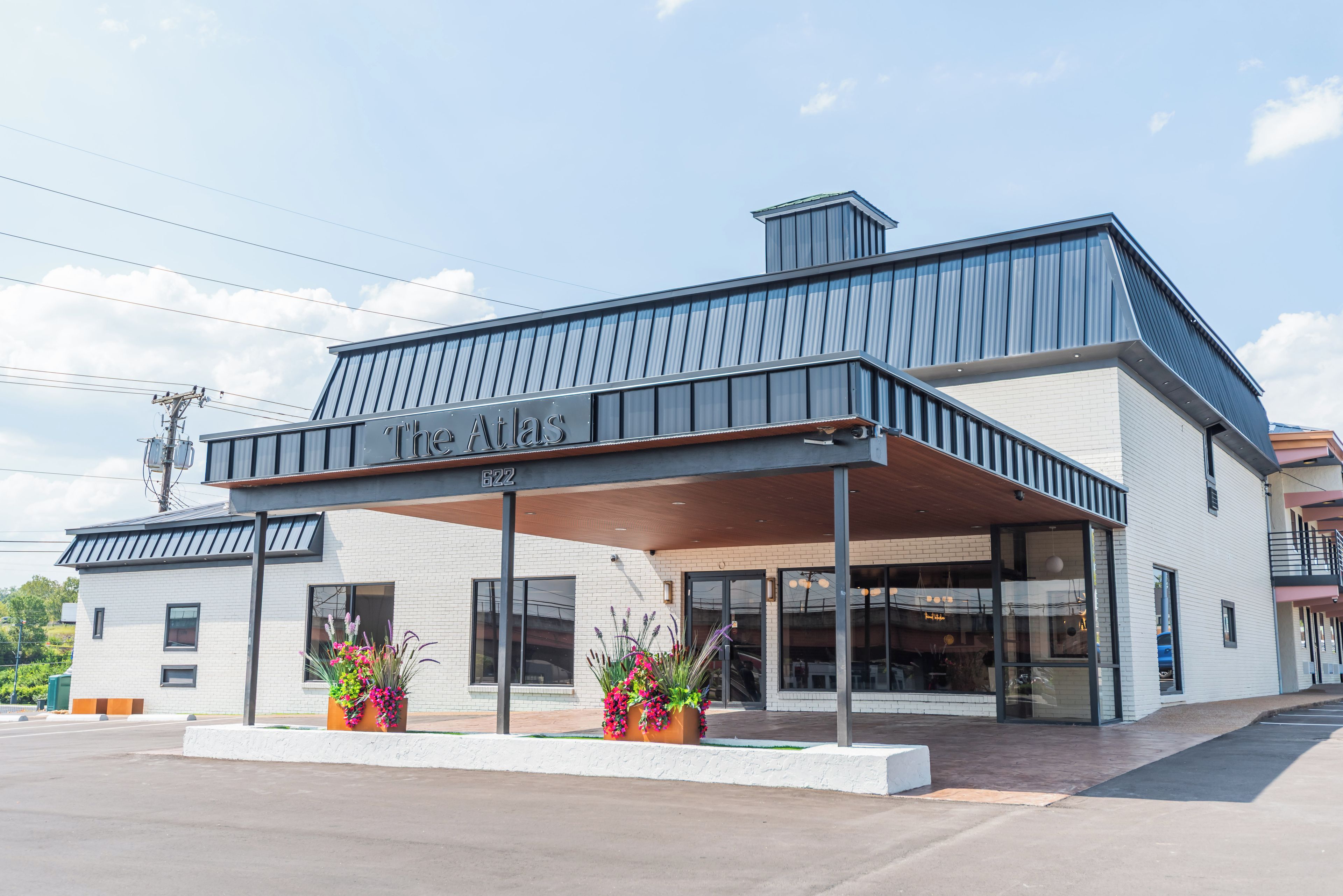 A modern building with a covered entrance, large windows, and a sign reading 'The Atlas.'
