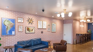A modern interior with a brick wall, a blue sofa, a coffee table, and a bar area with stools. -  The Atlas Hotel & Lofts (Goodlettsville)