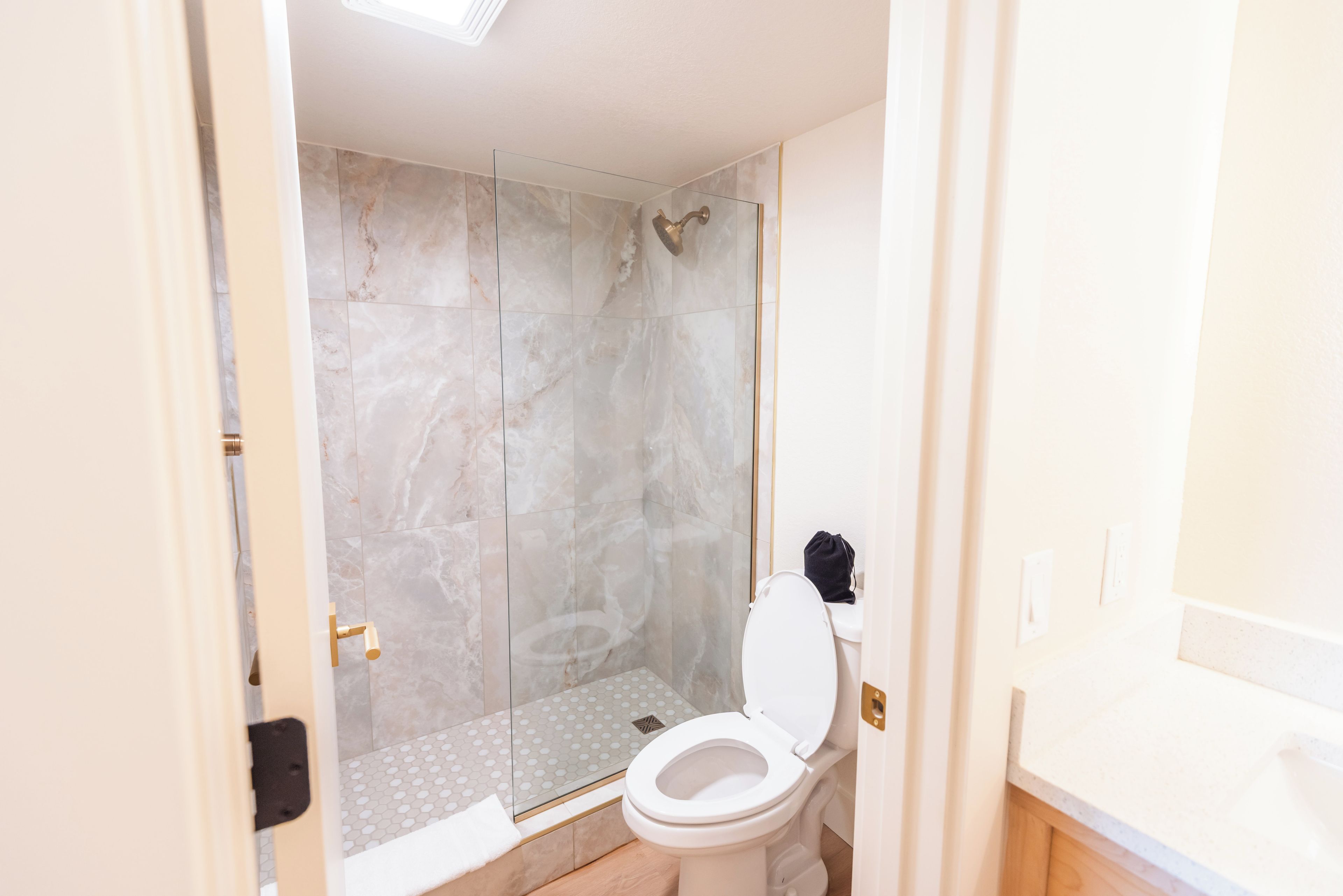 A bathroom with a shower, toilet, and a glass-enclosed shower area.