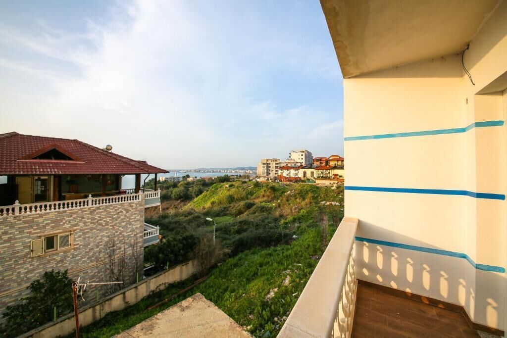 A balcony overlooking a hillside with a view of a distant building and a bridge.