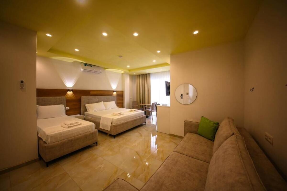Une chambre d’hôtel avec deux lits, un canapé, un miroir et une fenêtre.