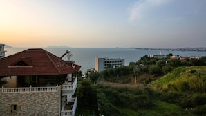 A coastal building with a red roof, a balcony, and a view of the sea and distant mountains. - Tonis Rooms Vlore (Vlore)