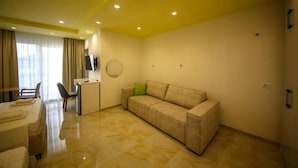 A hotel room with a sofa, a desk, a chair, and a TV on the wall. - Tonis Rooms Vlore (Vlore)