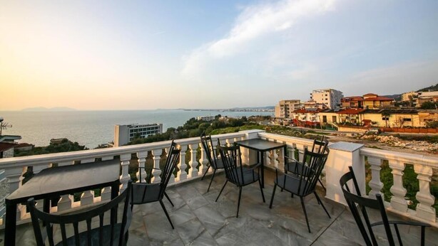 A terrace with outdoor seating, overlooking a coastal cityscape. - Tonis Rooms Vlore (Vlore)