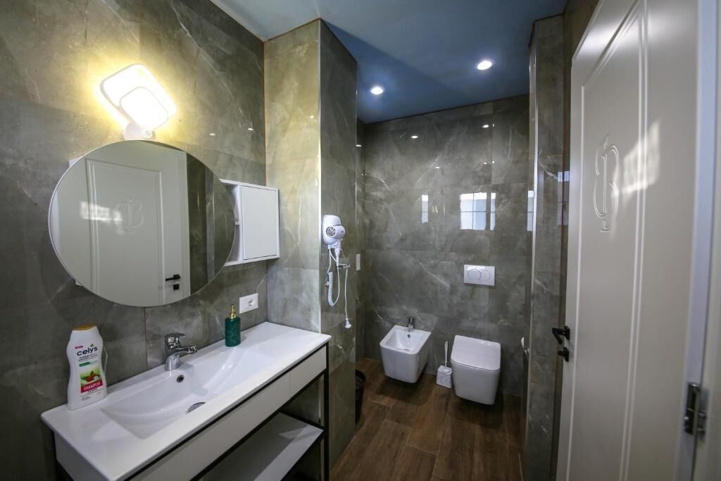 A modern bathroom with a white sink, mirror, and a bidet.