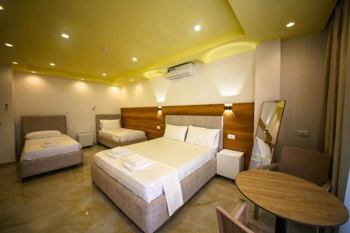Une chambre d’hôtel avec deux lits, une petite table, une chaise et un miroir.