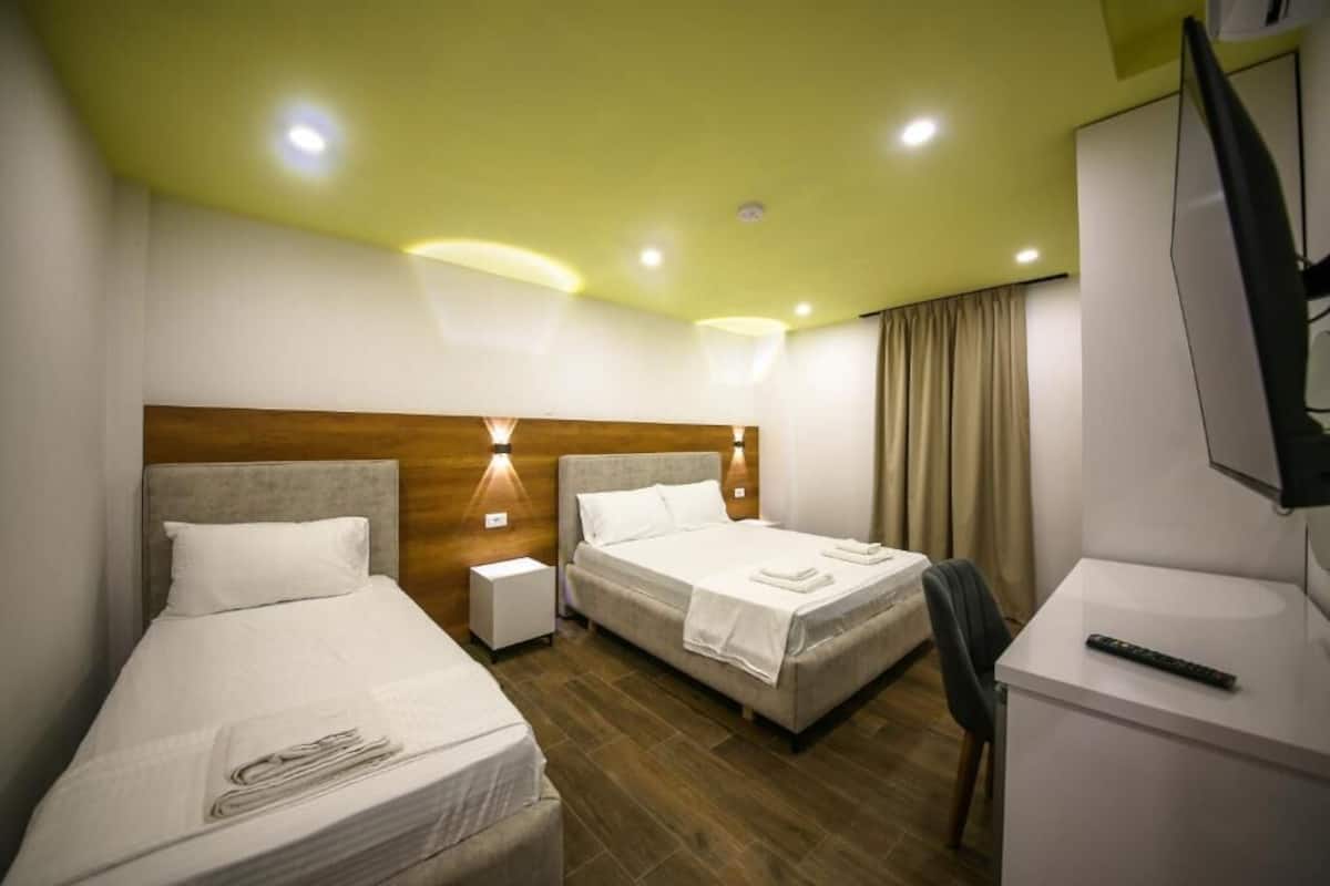 Une chambre d’hôtel avec deux lits, un bureau, une chaise et un téléviseur.