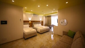 A hotel room with two beds, a sofa, a desk, and a clock on the wall. - Tonis Rooms Vlore (Vlore)