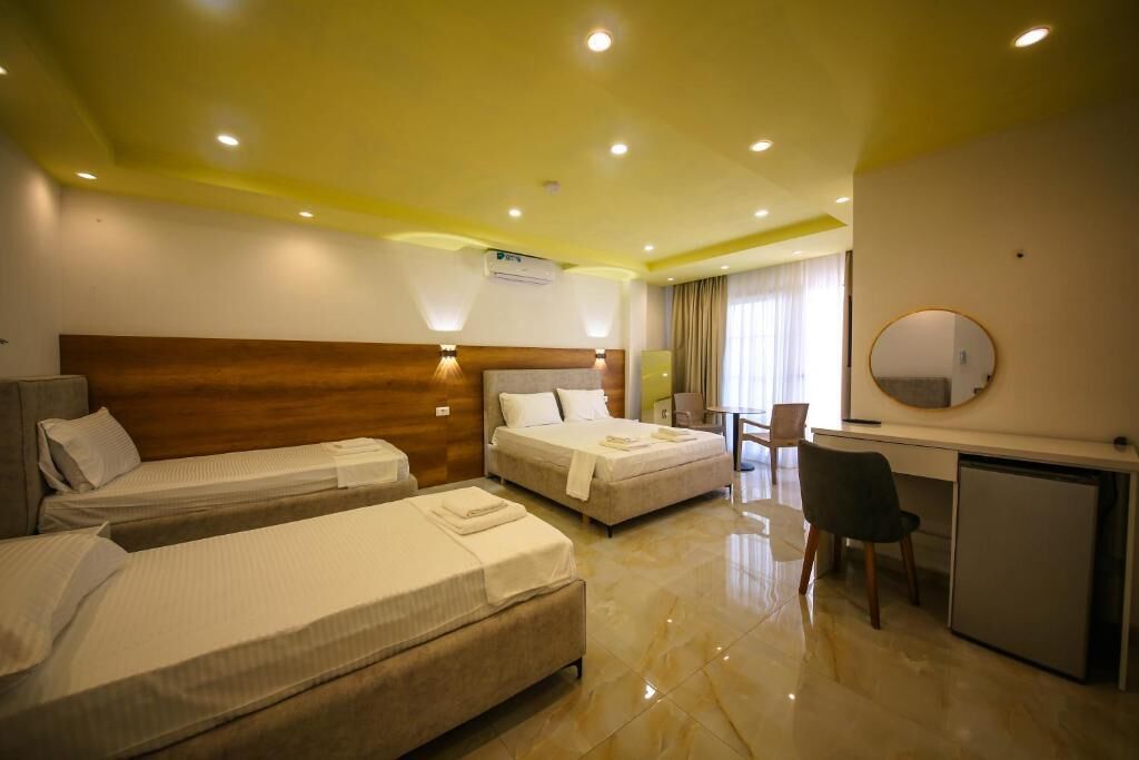 Habitación de hotel con dos camas, un escritorio, una silla y un refrigerador pequeño.