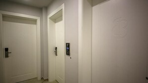 A hallway with white doors, one marked with the number 106, and a door with a number 3 embossed on it. - Tonis Rooms Vlore (Vlore)
