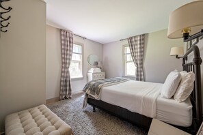 Une chambre à coucher avec un lit, une table de chevet, une lampe et une fenêtre avec des rideaux.