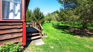 Eine Holzhütte mit Veranda, einem Rasen und einem Picknicktisch.