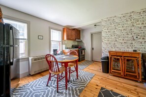 A compact kitchen with a dining area, a radiator, and a brick-patterned wall.
