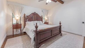 Ein Schlafzimmer mit einem hölzernen Himmelbett, einem Deckenventilator und zwei Nachttischlampen.