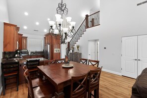 A spacious kitchen with wooden cabinets, a dining table with chairs, and a staircase leading to another level. - 3BR Pet-Friendly Condo w/ Pool & Views (St. George)
