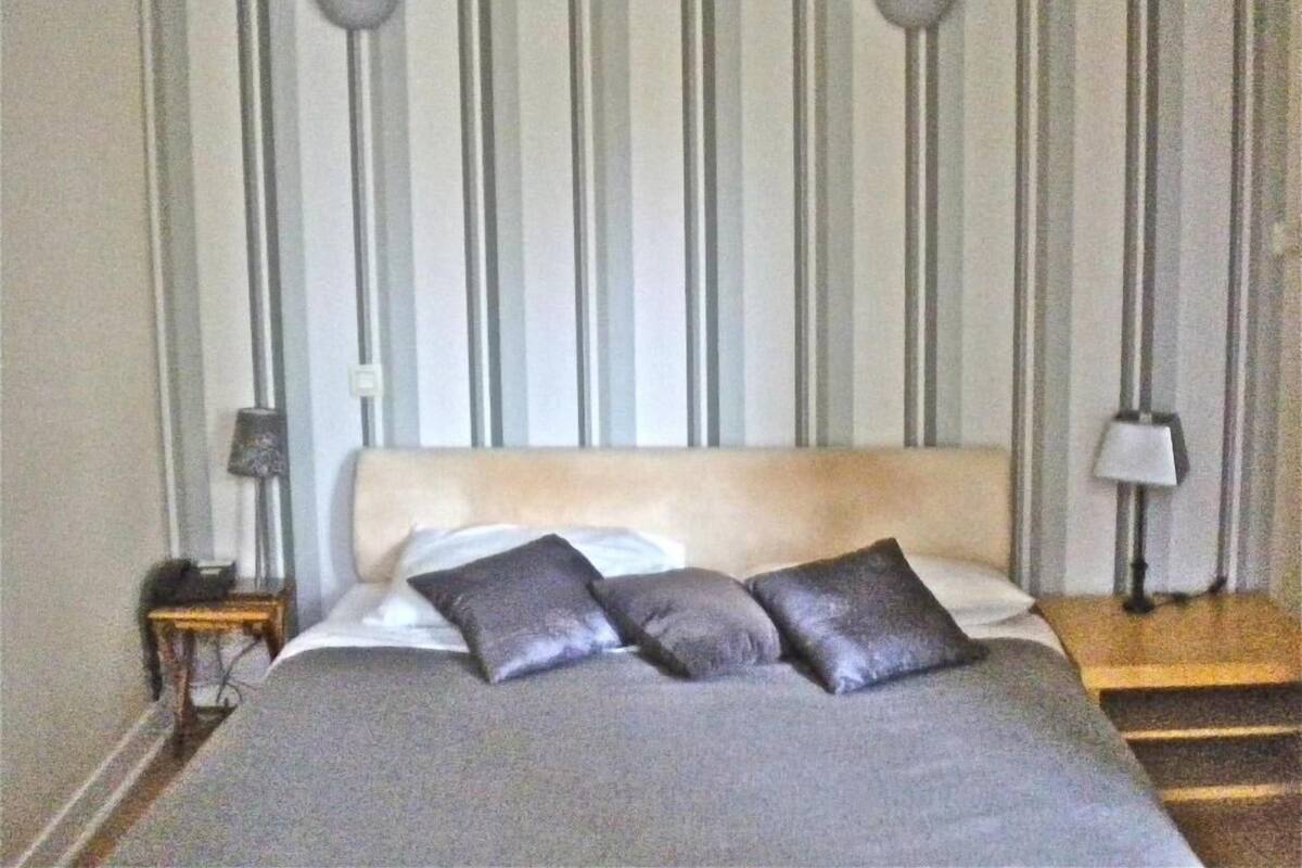 A bed with a headboard, two pillows, a nightstand with a lamp, and a striped wall.