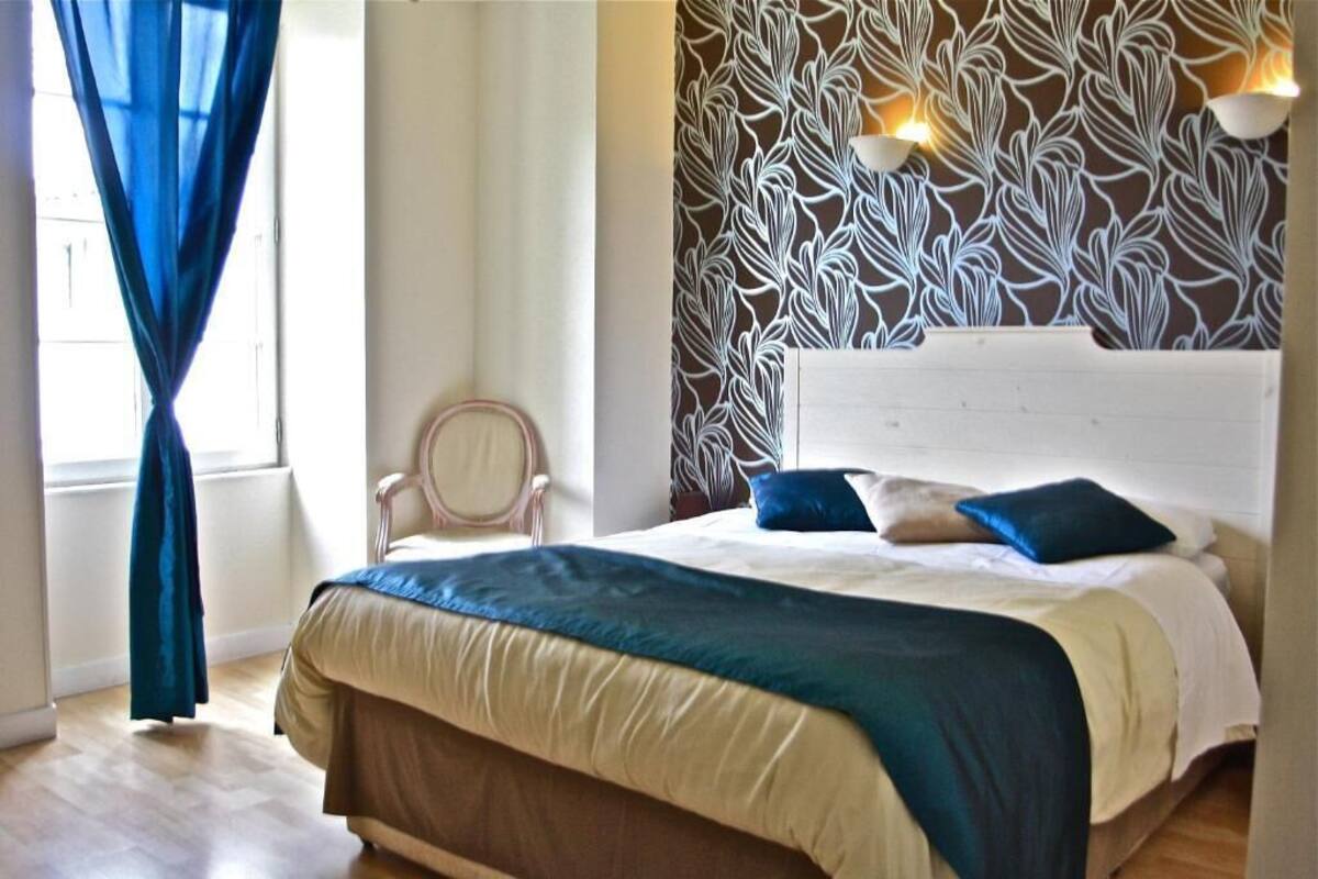 A bedroom with a bed, a chair, and a patterned wall.