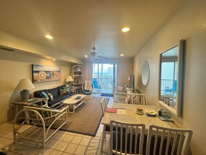 Un espace de vie comprenant un canapé, une table basse, une table à manger, des chaises, un téléviseur et un balcon avec vue.