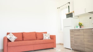 A modern kitchen with white cabinets, a wooden countertop, and a red sofa with patterned cushions. - Country House Frantoiano (ROSIGNANO MARITTIMO)