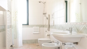 A bathroom with a toilet, bidet, sink, and shower. - Country House Frantoiano (ROSIGNANO MARITTIMO)
