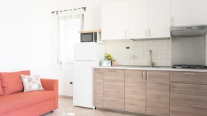A modern kitchen with white cabinets, a microwave, and a stove. - Country House Frantoiano (ROSIGNANO MARITTIMO)
