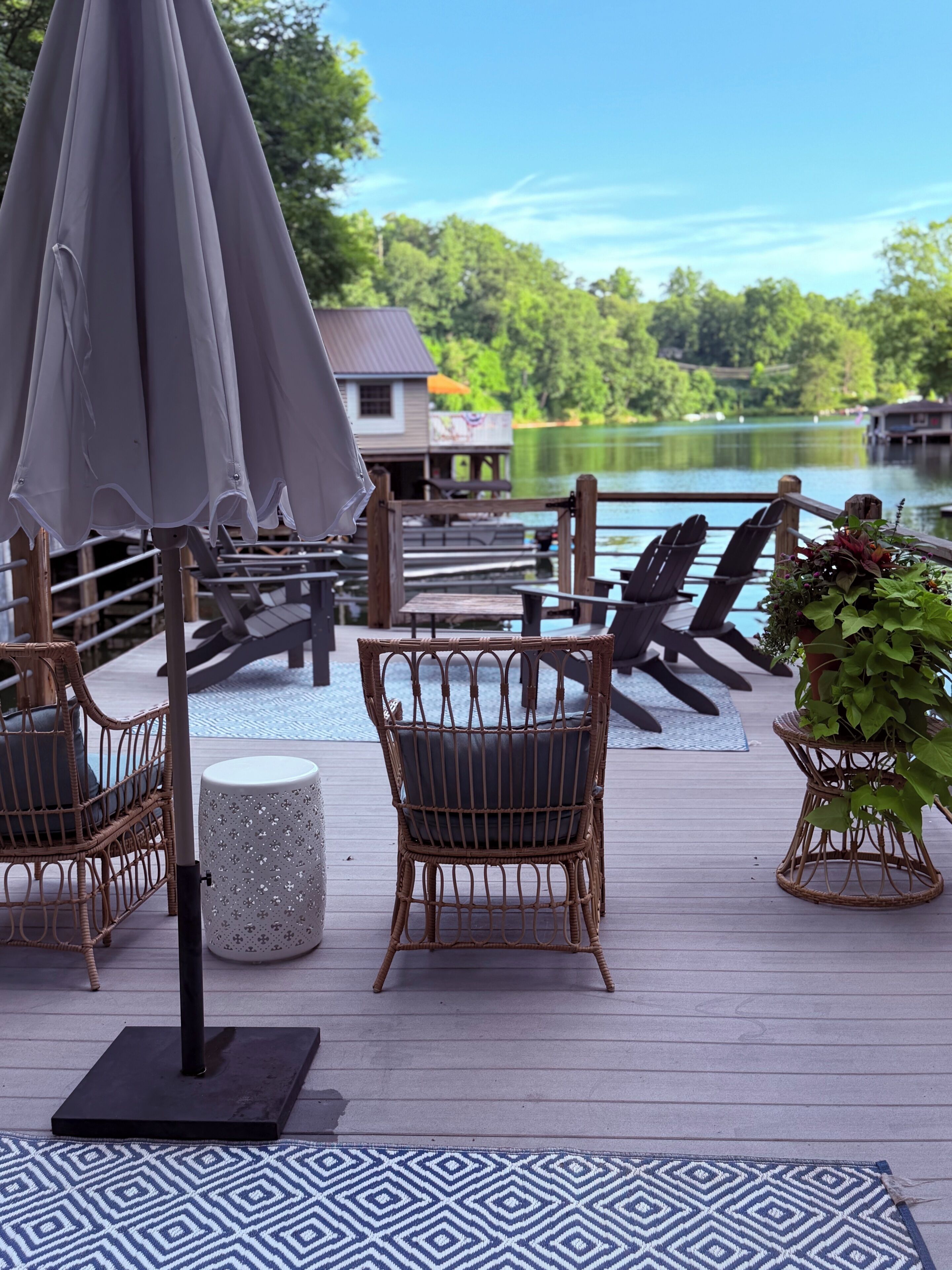 A deck with wicker chairs, a table, and a potted plant.
