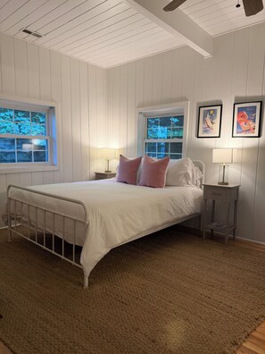 A bedroom with a bed, two bedside tables, a window, and a ceiling fan. - Lakefront Lake Lure Cabin: Private Dock, Paddleboards, Firepit Near Chimney Rock (Lake Lure)