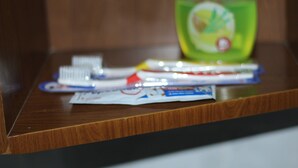 Uma superfície de madeira com uma escova de dentes, creme dental e um frasco de enxaguante bucal.