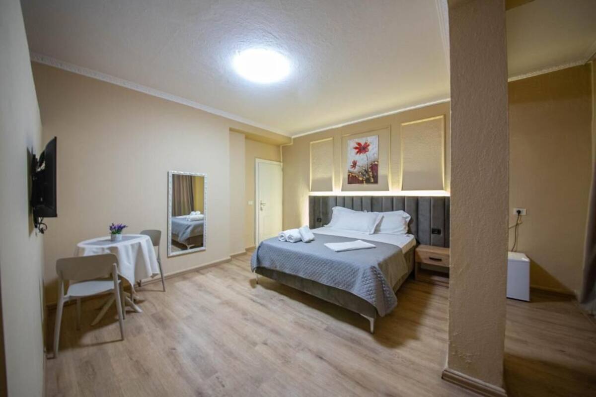 Un dormitorio con cama, una silla, una mesita y un espejo.