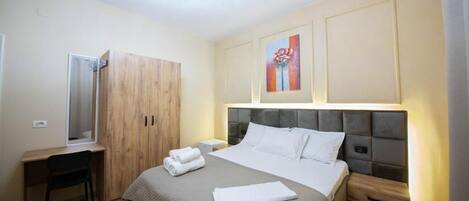 Habitación de hotel con cama, escritorio, armario y un cuadro en la pared.