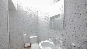 A bathroom with a white sink, toilet, and a mirror on the wall. - Eriks Rooms (Tirana)