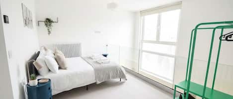 A bedroom with a bed, a radiator, a window, and a green bench.