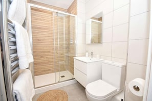 Ein modernes Badezimmer mit Duschkabine aus Glas, einem weißen Waschbecken und einer Toilette.