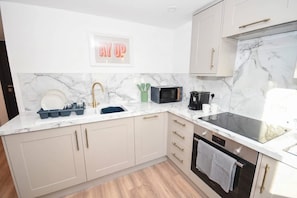 A modern kitchen with marble countertops, a built-in microwave, a coffee maker, and a toaster. - Modern 1 Bedroom Central Leeds Mezzanine Apartment (Leeds)