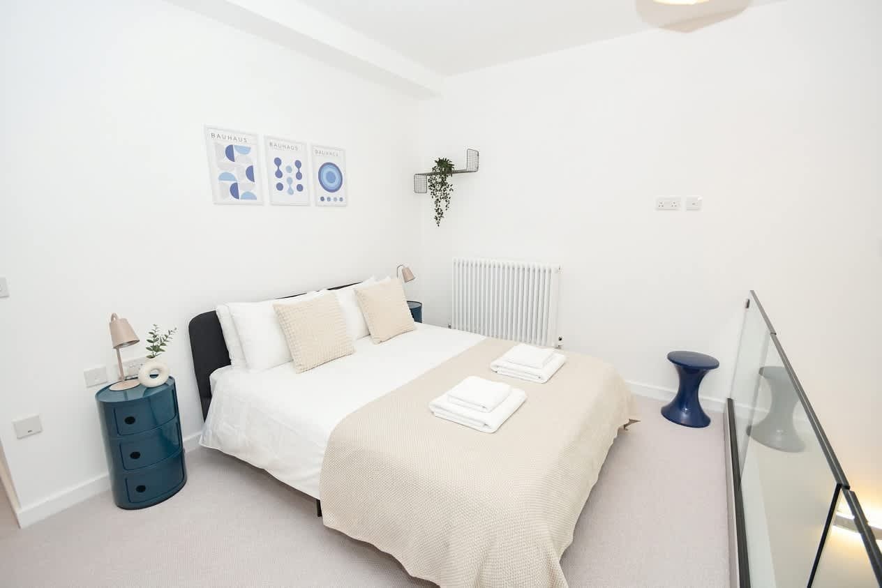 A modern bedroom with a bed, bedside table, and a wall-mounted plant.