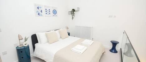 A modern bedroom with a bed, bedside table, and a wall-mounted plant.