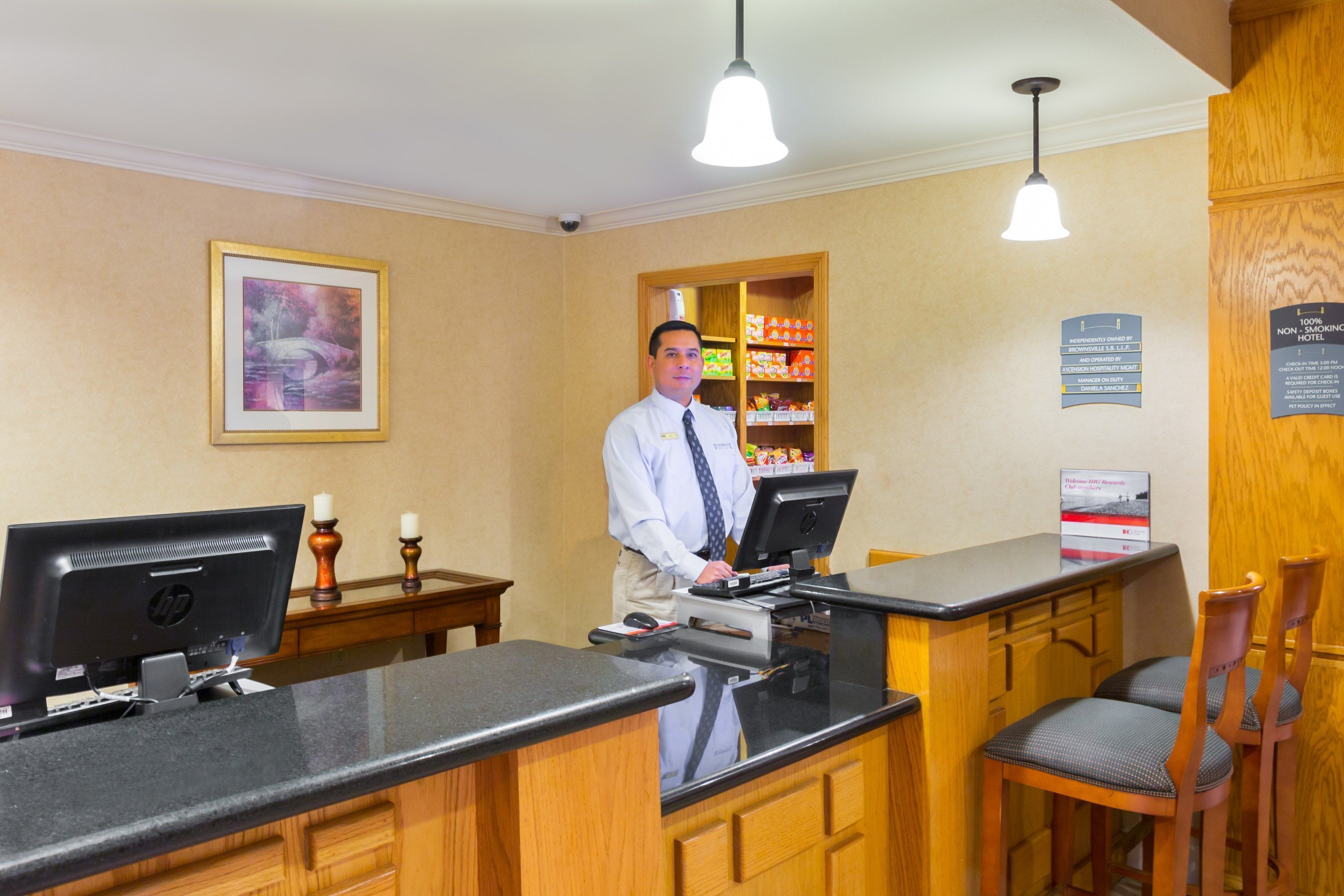 A hotel reception desk with a computer, a cash register, and a sign indicating a non-smoking policy.