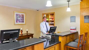 A hotel reception desk with a computer, a cash register, and a sign indicating a non-smoking policy.