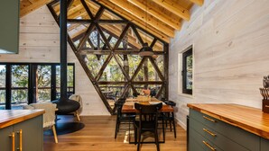 Un interior de madera con comedor, ventanas amplias y chimenea.