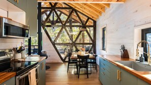 Una cocina moderna con una isla central, electrodomésticos integrados y un ventanal grande con un marco geométrico.
