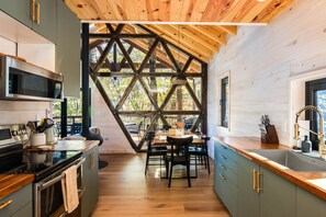 Eine moderne Küche mit einer zentralen Kochinsel, eingebauten Geräten und einem großen Fenster mit geometrischem Rahmen.