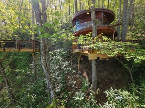 A treehouse with a wooden deck and a small platform. - Mushroom-Inspired Treehouse with Living Roof - The Mēos (Highlands)