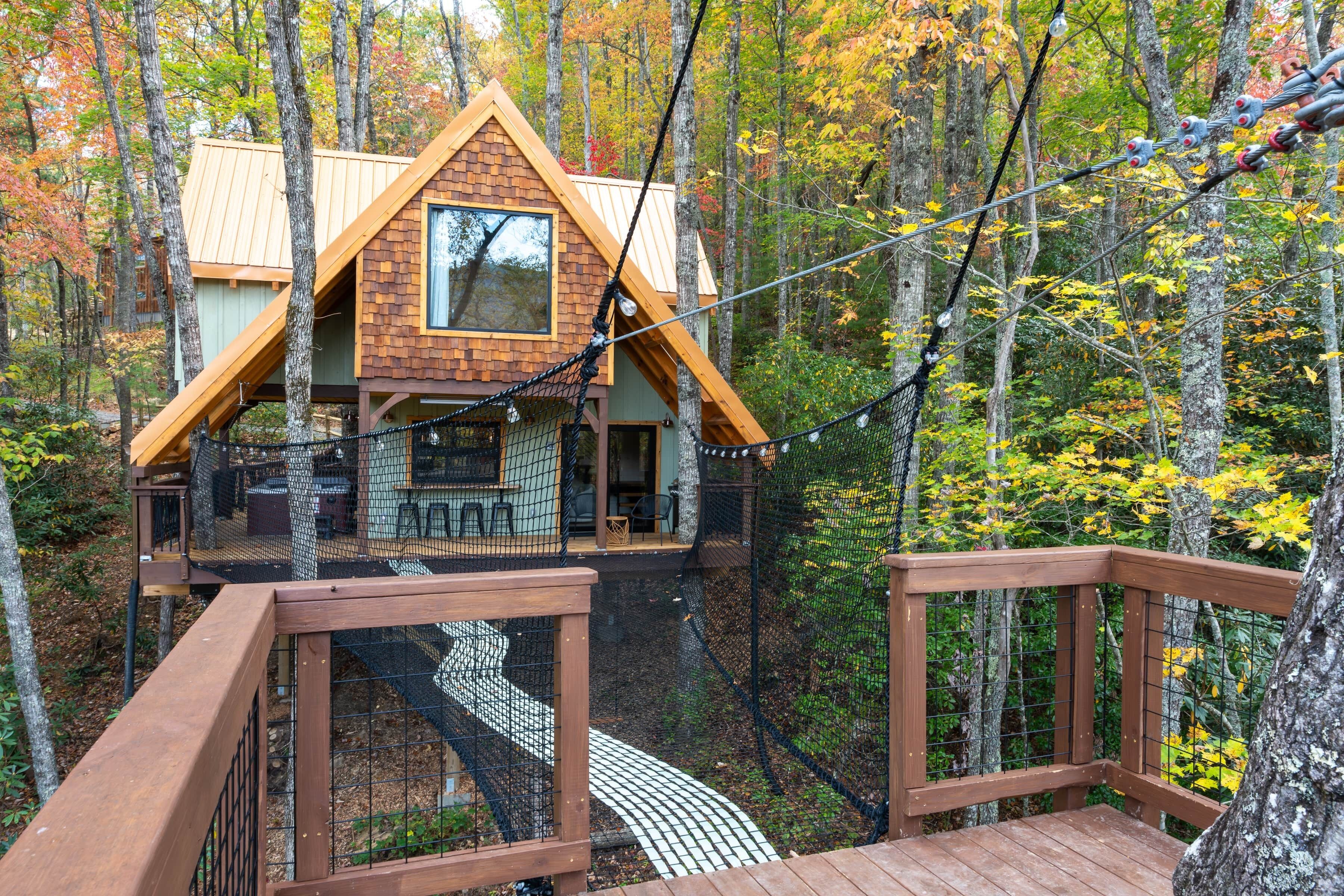 A cabin with a wooden deck and a rope bridge.