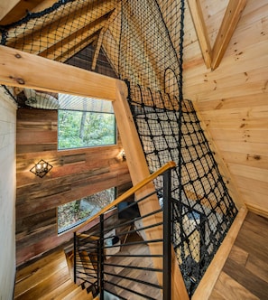 Ein Holzinnenraum mit einer Wendeltreppe, Holzwänden und einem Fenster mit Blick auf Bäume.