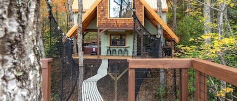 Una cabaña de madera con techo inclinado, una ventana y una terraza.