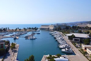 Un port de plaisance où sont amarrés de nombreux bateaux, entouré de bâtiments et offrant une vue dégagée sur la mer.
